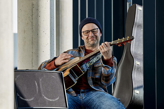 Ein Mann kniet in Rockstar-Pose und spielt akustische Gitarre.