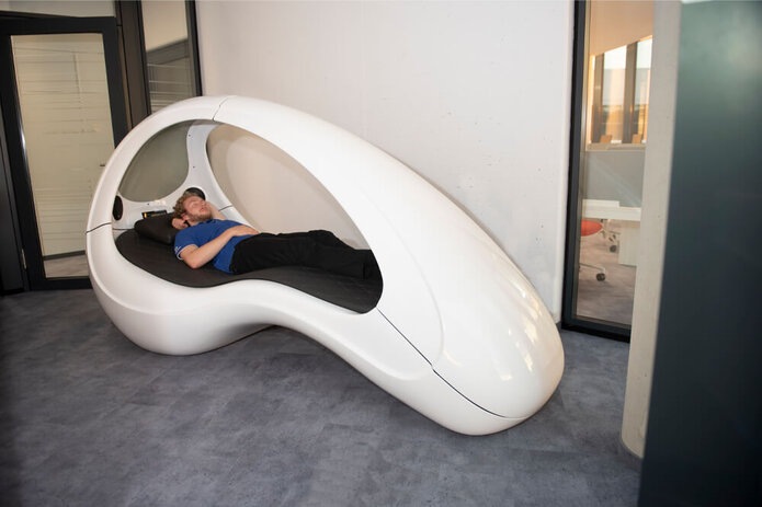 In the wellness area: A young man is lying in a plastic capsule that is open on the sides.