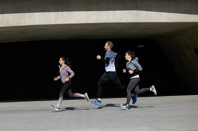 Several joggers are running alongside the building.